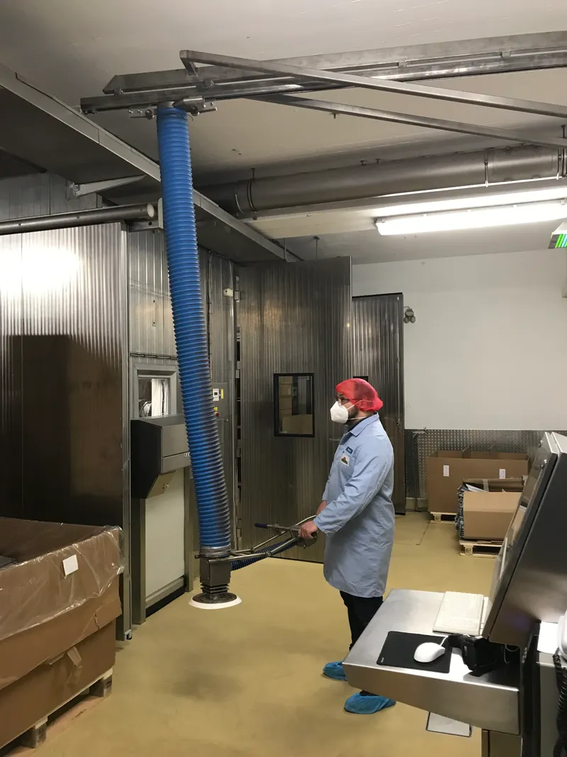 Operator guiding an ezzFAST vacuum lifter in a hygienic production area.